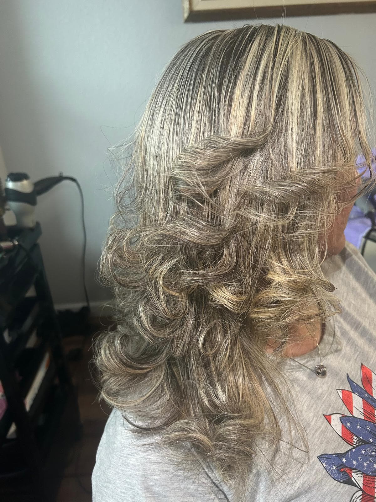 Mechas rubio ceniza en un corte en capas, peinado con rizos sueltos.
